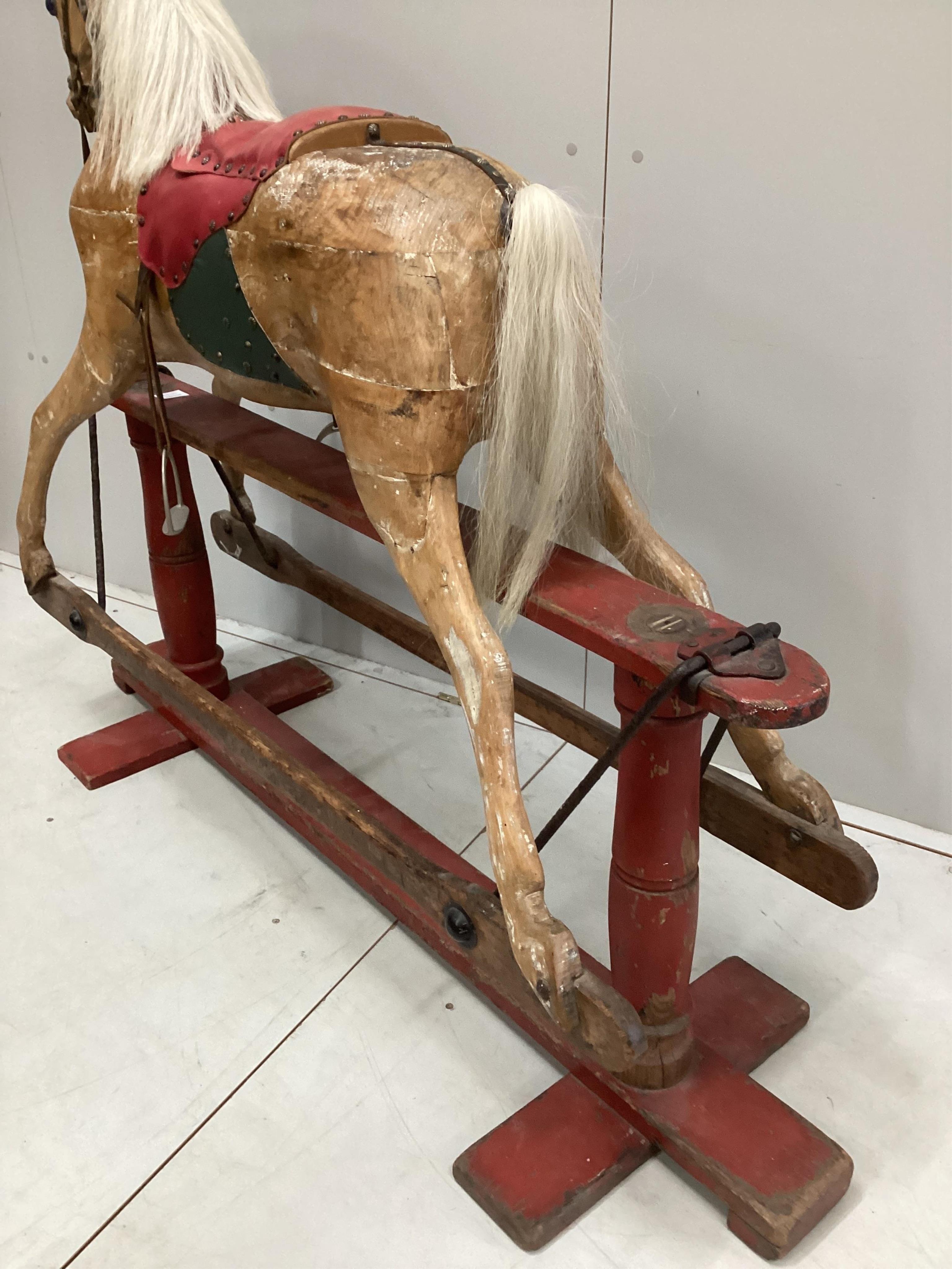 An early 20th century carved wood rocking horse on stand (a.f.), 117cm high, base of stand 146 wide